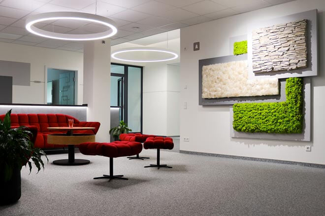 Lounge im Büro von IBWeigert mit roten Sitzmöbeln und begrünten Wandelementen