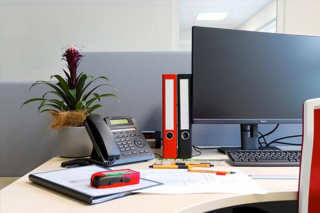 Arbeitsplatz im Büro von IBWeigert mit Bauplänen, Ordnern und Telefon